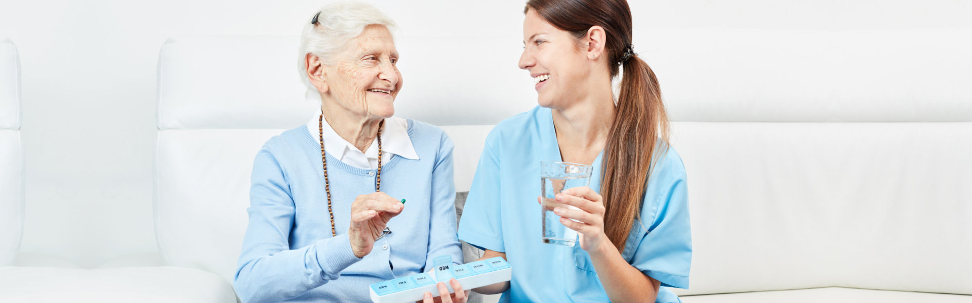 nurse assisting senior woman in drinking medicine